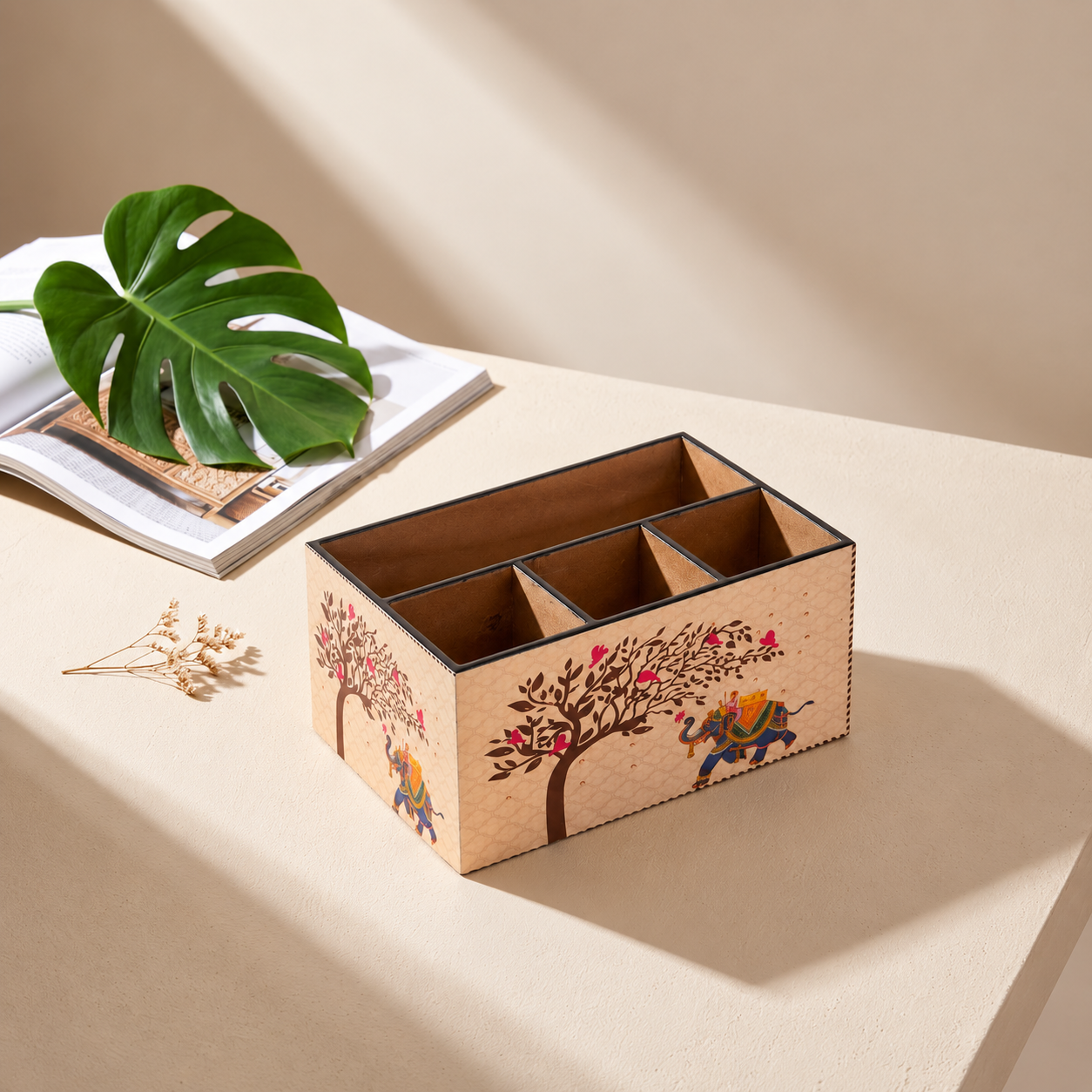 Decorative wooden cutlery organiser with elephant and tree artwork on a sunlit tabletop